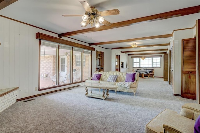 living room featuring wood walls, ceiling fan, beam ceiling, and light colored carpet