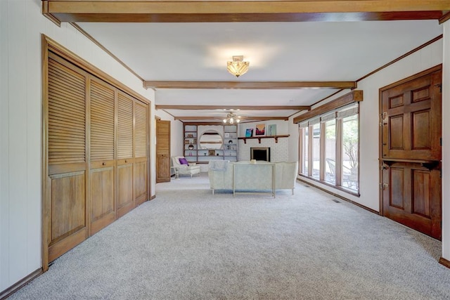 living room with beamed ceiling, light colored carpet, ornamental molding, and a brick fireplace