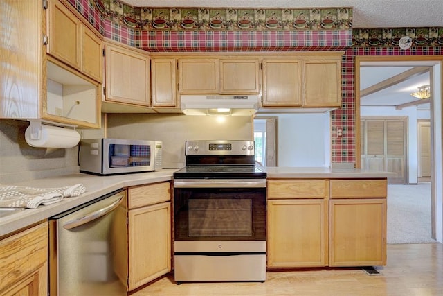 kitchen featuring a textured ceiling, stainless steel appliances, light brown cabinetry, and light hardwood / wood-style flooring