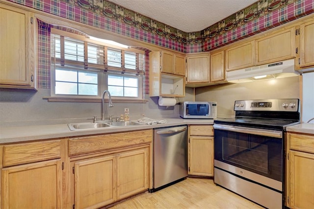 kitchen featuring light brown cabinetry, light wood-type flooring, a textured ceiling, stainless steel appliances, and sink