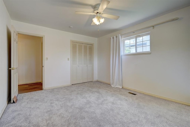 unfurnished bedroom featuring ceiling fan, a closet, and light colored carpet