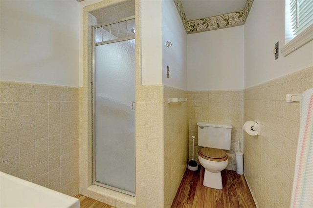 bathroom featuring hardwood / wood-style flooring, toilet, a shower with door, and tile walls