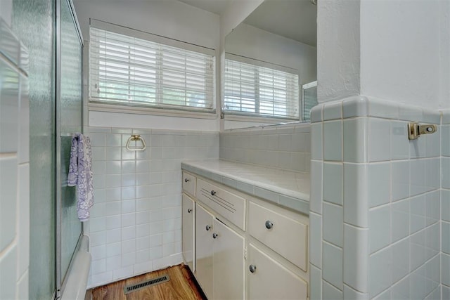 bathroom featuring wood-type flooring, vanity, and tile walls