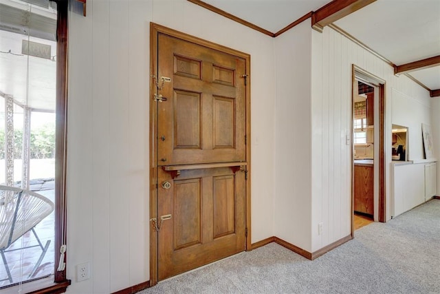 entrance foyer featuring light carpet, beam ceiling, wooden walls, and ornamental molding