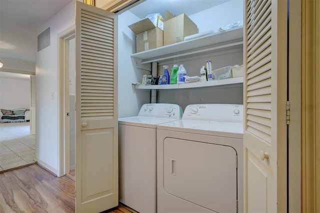 clothes washing area featuring washer and clothes dryer and light wood-type flooring