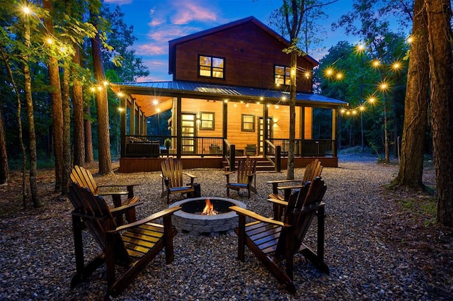 back house at dusk featuring a porch and a fire pit