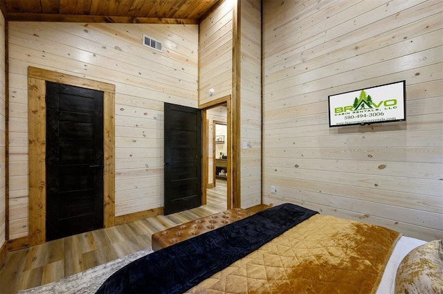 bedroom featuring lofted ceiling, hardwood / wood-style floors, wood ceiling, and wood walls