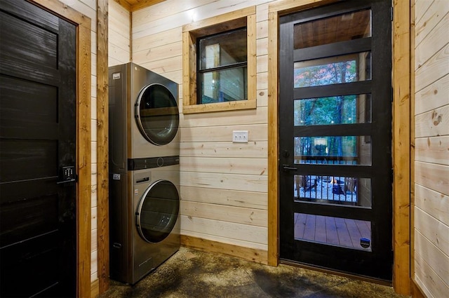 laundry room featuring stacked washing maching and dryer and wood walls