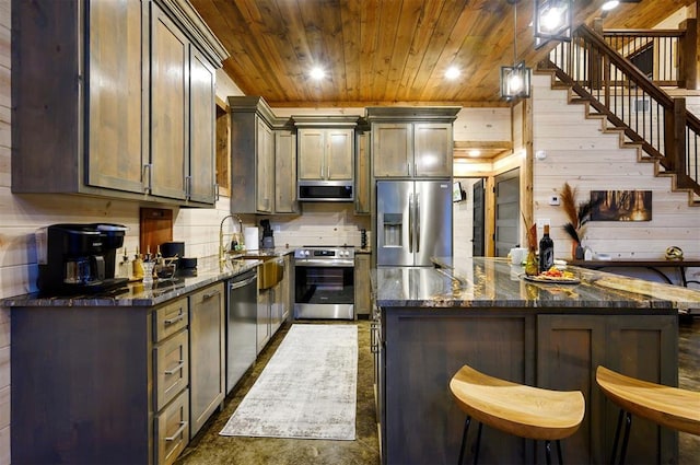 kitchen featuring wood ceiling, a breakfast bar area, appliances with stainless steel finishes, dark stone countertops, and hanging light fixtures