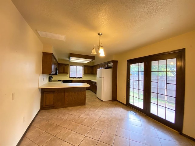 kitchen featuring kitchen peninsula, white refrigerator, an inviting chandelier, and plenty of natural light