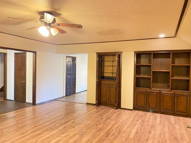 unfurnished living room featuring ceiling fan, light hardwood / wood-style floors, and a textured ceiling