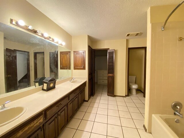 full bathroom with tile patterned floors, a textured ceiling, toilet, vanity, and tiled shower / bath