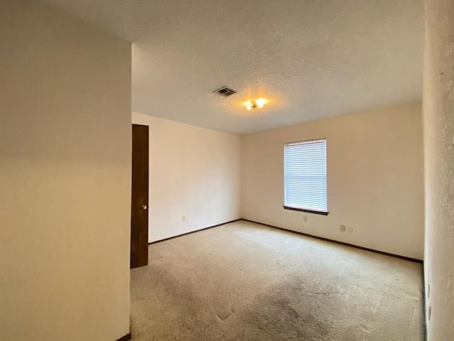 spare room with light colored carpet and a textured ceiling