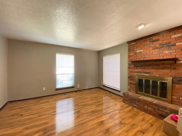 unfurnished living room featuring a fireplace, wood-type flooring, and a textured ceiling