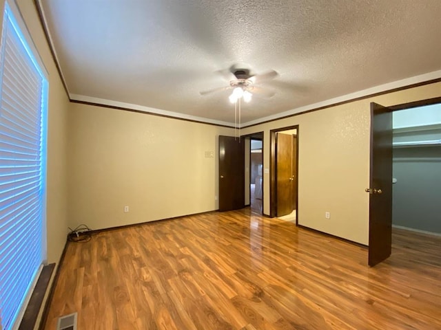 unfurnished bedroom with a textured ceiling, light hardwood / wood-style floors, ceiling fan, and crown molding