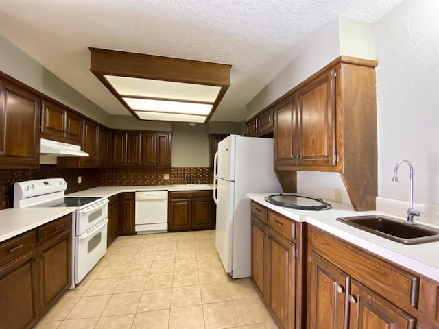 kitchen featuring a textured ceiling, decorative backsplash, white appliances, and sink