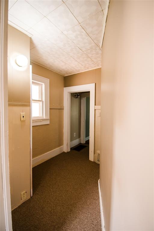 corridor featuring dark colored carpet