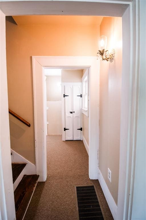 corridor featuring carpet flooring and an inviting chandelier