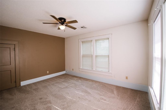 carpeted spare room featuring plenty of natural light and ceiling fan