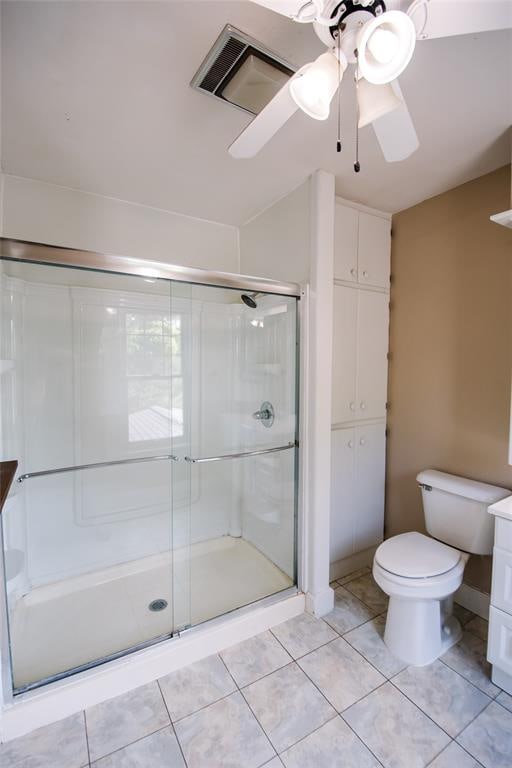 bathroom featuring tile patterned flooring, ceiling fan, toilet, and an enclosed shower