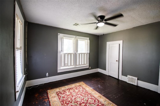 empty room with ceiling fan, dark hardwood / wood-style flooring, and a textured ceiling