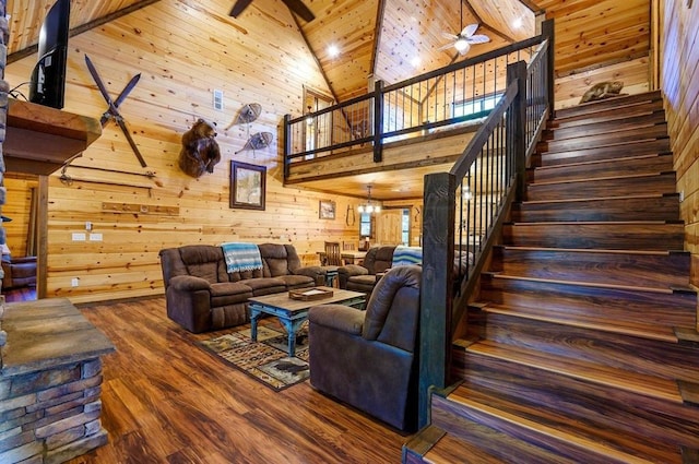 living room with ceiling fan with notable chandelier, high vaulted ceiling, wooden ceiling, hardwood / wood-style floors, and wood walls