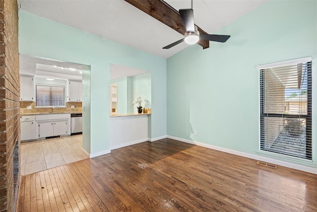 unfurnished living room featuring vaulted ceiling with beams, ceiling fan, sink, and light wood-type flooring