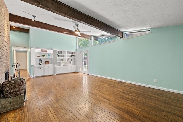 living room featuring beam ceiling, wood-type flooring, and a textured ceiling