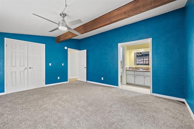 unfurnished bedroom with ceiling fan, sink, lofted ceiling with beams, light colored carpet, and a closet