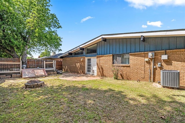 back of house with a yard, a fire pit, and cooling unit