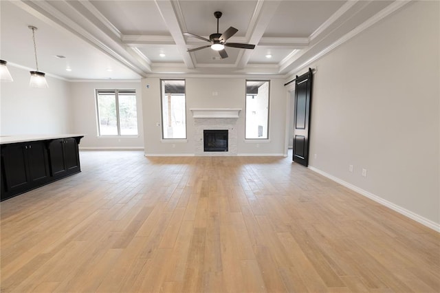 unfurnished living room with crown molding, ceiling fan, beam ceiling, a barn door, and coffered ceiling