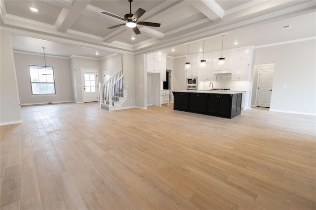 unfurnished living room with coffered ceiling, ceiling fan, crown molding, beam ceiling, and light hardwood / wood-style flooring