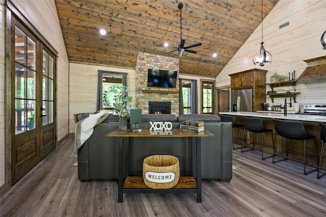 living room with ceiling fan, dark hardwood / wood-style floors, wood walls, and high vaulted ceiling