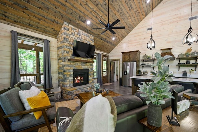 living room featuring ceiling fan with notable chandelier, wood-type flooring, high vaulted ceiling, a fireplace, and wood walls