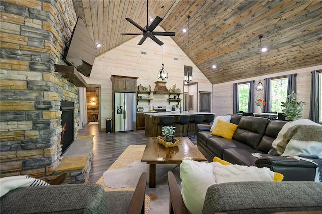 living room with ceiling fan, dark hardwood / wood-style flooring, high vaulted ceiling, wood walls, and a fireplace