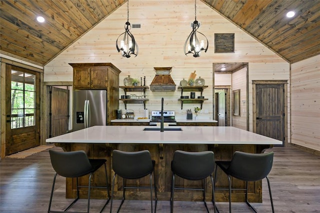 kitchen featuring wooden walls, decorative light fixtures, wood ceiling, and appliances with stainless steel finishes