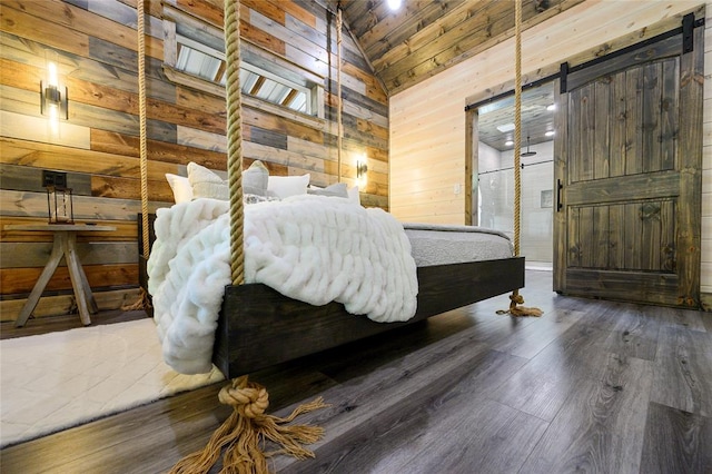 bedroom featuring wood walls, lofted ceiling, wooden ceiling, dark hardwood / wood-style floors, and a barn door