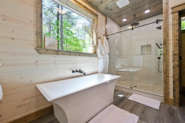 bathroom with wood-type flooring, separate shower and tub, and wood walls