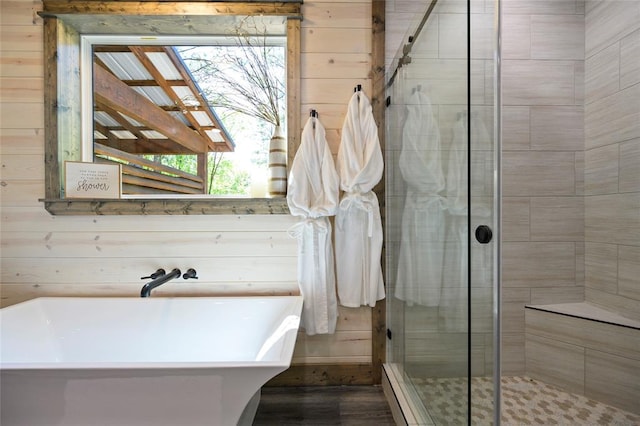 bathroom featuring hardwood / wood-style floors, independent shower and bath, and wooden walls