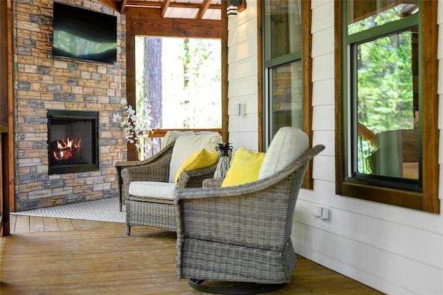 sitting room with wood-type flooring, an outdoor stone fireplace, and wooden walls