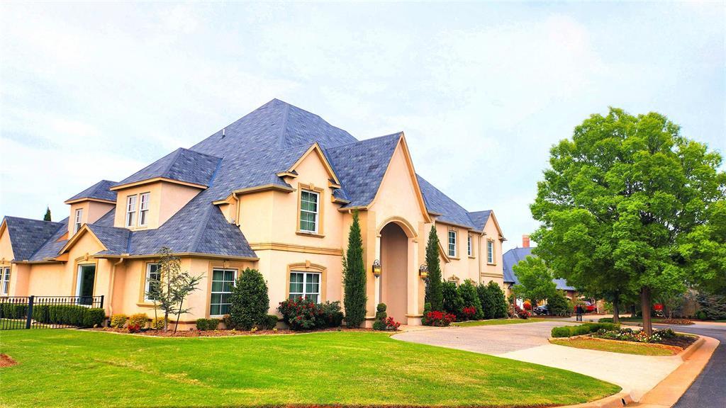 french country inspired facade featuring fence, a high end roof, stucco siding, and a front lawn