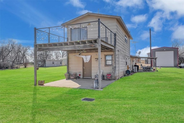 back of house with an outdoor structure, a garage, a yard, and a patio