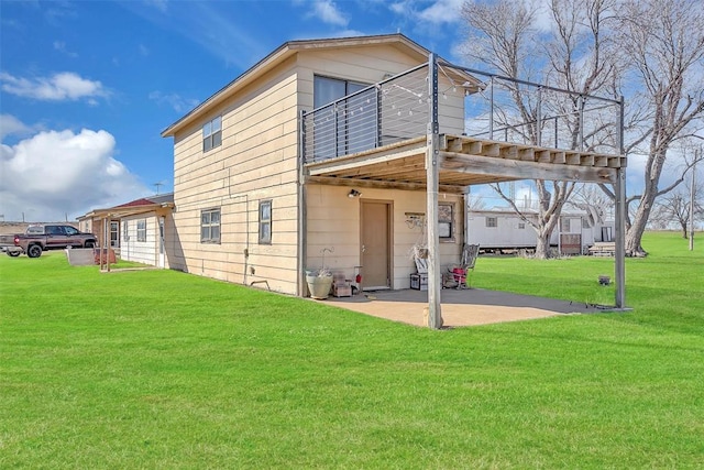 rear view of house featuring a yard, a balcony, and a patio area