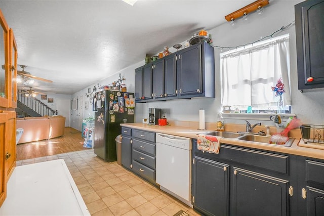 kitchen featuring white dishwasher, black fridge, sink, ceiling fan, and light wood-type flooring