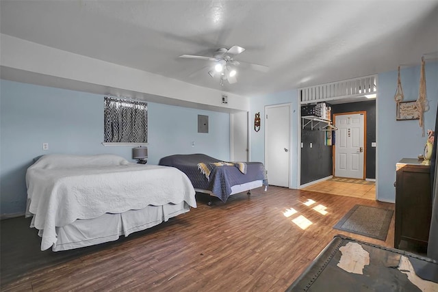 bedroom with electric panel, hardwood / wood-style flooring, and ceiling fan