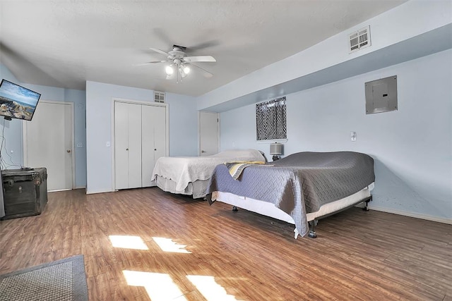 bedroom featuring hardwood / wood-style flooring, ceiling fan, and electric panel