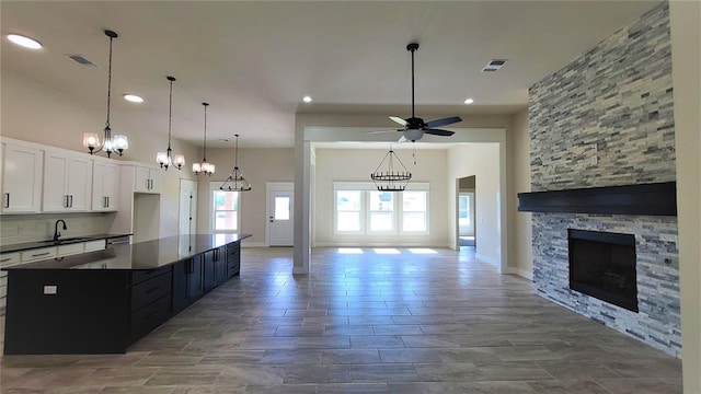 kitchen with sink, hanging light fixtures, ceiling fan, a fireplace, and white cabinetry