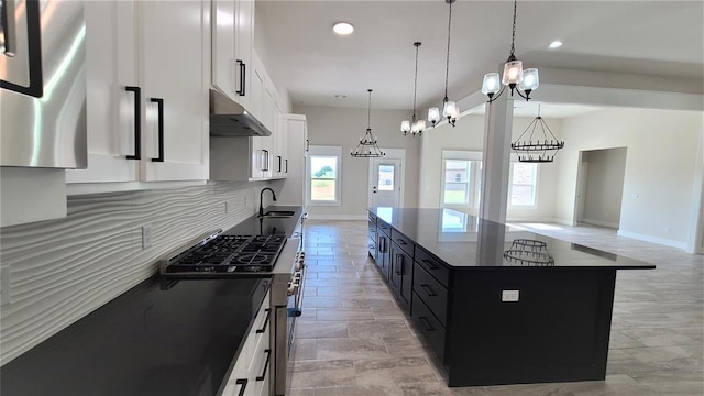 200 Braxton Way, Yukon, OK 73099 - kitchen with under cabinet range hood, dark cabinetry, a sink, a chandelier, and stainless steel range