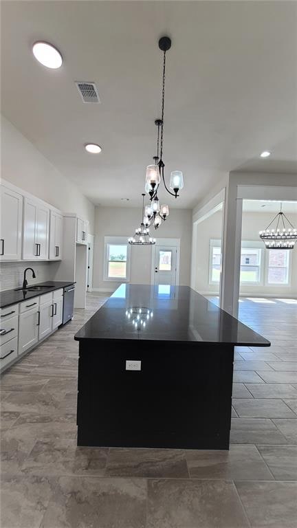 kitchen with white cabinetry, a center island, sink, stainless steel dishwasher, and pendant lighting