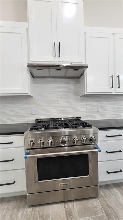 kitchen with tasteful backsplash, white cabinetry, stainless steel range, and light hardwood / wood-style floors